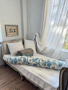 a bed sitting in front of a window next to a wooden floor