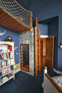 a bedroom with a bed, bookshelf and climbing net in it's corner