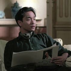 a man sitting on a couch reading a paper