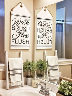 two bathroom signs hanging on the wall above a sink with flowers in front of it