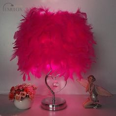 a pink lamp sitting on top of a table next to a vase filled with flowers