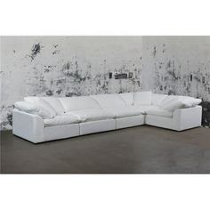 a white leather sectional sofa in front of a wall with black and white paint on it