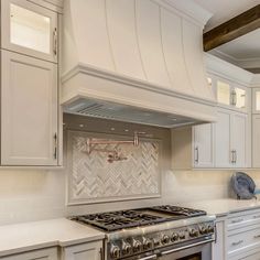 a stove top oven sitting inside of a kitchen next to white cabinets and counter tops