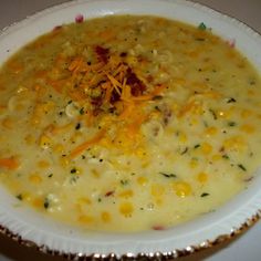 a white bowl filled with soup and cheese on top of a table next to a spoon