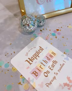 a happy birthday sign and disco balls on a table with confetti around it