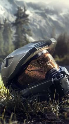 a helmet sitting on the ground in front of some grass and trees with mountains in the background