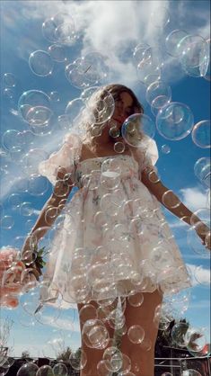 a woman in a white dress is surrounded by bubbles