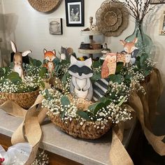 two baskets filled with fake animals sitting on top of a counter covered in greenery