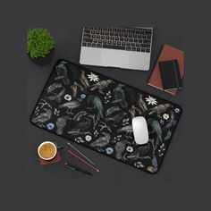 a computer mouse pad with an image of birds and flowers on it next to a cup of coffee