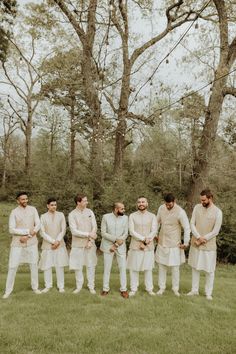 a group of men standing next to each other on top of a lush green field