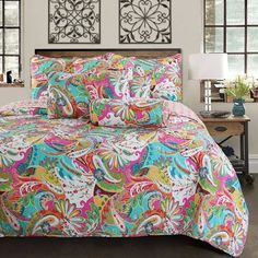 a bed with colorful comforters and pillows in a room