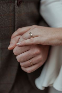 a man and woman holding hands while wearing wedding rings