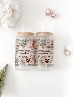 two candles sitting next to each other on top of a white table with pink flowers