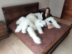 a woman sitting on top of a bed covered in giant white furry animal arms and legs