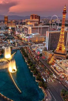 the las vegas strip at dusk with fountains and ferris wheel in the foreground, including the eiffel tower