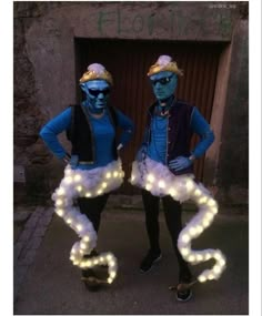 two people dressed in costumes with lights on their legs and arms, standing next to each other