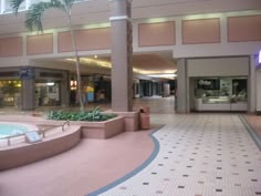 the inside of a shopping mall with palm trees in the center and tiled flooring