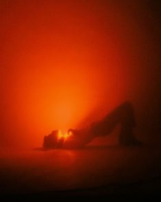 a person laying on the ground in front of a bright orange light that is shining