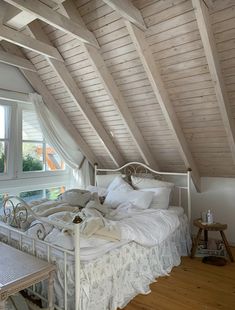 a bed sitting under a window in a bedroom next to a wooden table and chair