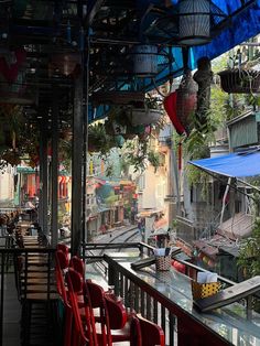 an outdoor restaurant with red chairs and blue awnings on the outside, overlooking a city street