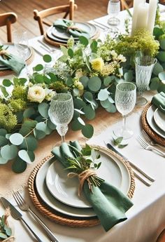 the table is set with plates, silverware and greenery for an elegant look