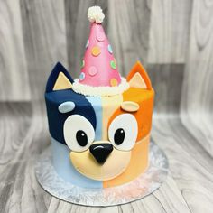 a colorful cake with a dog wearing a party hat on top of it's head