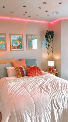 a white bed sitting in a bedroom next to two lamps and pictures on the wall