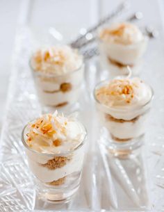 three small desserts are sitting on a glass tray with spoons in the background