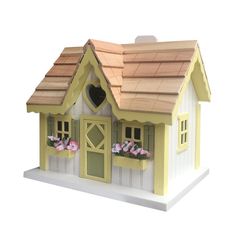 a small yellow and white birdhouse with flowers in the window boxes on it's roof