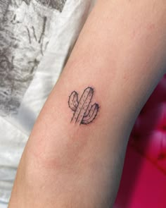 a small cactus tattoo on the arm