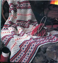 a knitted blanket sitting on top of a chair next to a pair of gloves