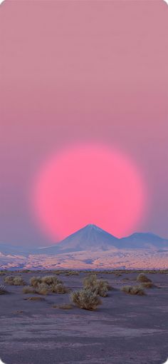 the sun is setting over mountains in the distance, with pink sky and purple clouds