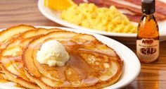 pancakes and waffles with syrup are on the table next to eggs, bacon, and orange juice