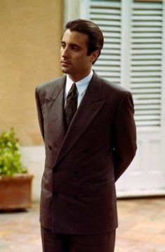 a man in a suit and tie standing on a brick floor next to a building