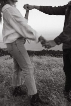 two people holding hands in the middle of a field