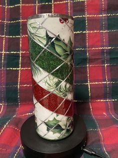 there is a vase that has been decorated with green leaves and red glitter on it