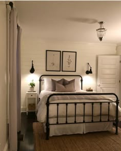 a bedroom with white walls and black iron bed frame