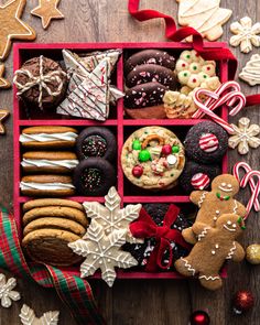 a red box filled with lots of different types of cookies and other holiday treats on top of a wooden table