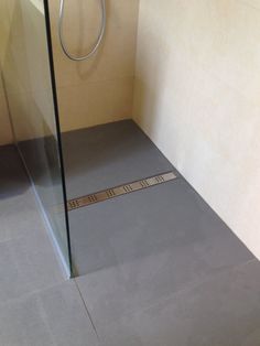 a bathroom with a glass shower door next to a toilet paper roll on the floor