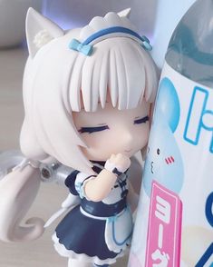 an anime figurine is posed next to a water bottle