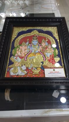 an ornate painting on display in a glass case with gold trimmings and black frame