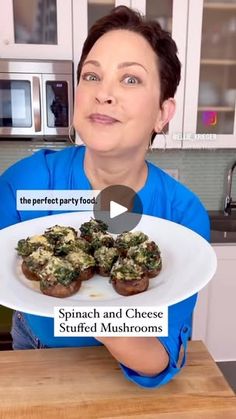 a woman holding a plate with stuffed mushrooms on it