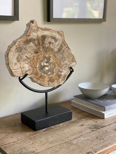 a piece of wood sitting on top of a wooden table next to a bowl and framed pictures