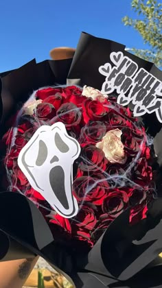 a bouquet of red roses with a ghost sticker on it