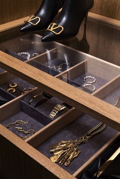 a pair of black high heeled shoes sitting on top of a wooden table filled with jewelry