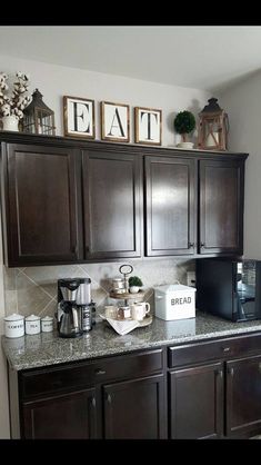 a kitchen with dark wood cabinets and white appliances on the counter top, along with pictures above it