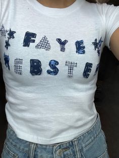 a woman wearing a white tshirt with blue letters on it