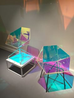 three glass tables sitting on top of each other in front of a wall with light coming through them