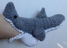 a crocheted stuffed shark is hanging on the wall next to a person's arm