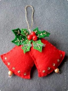 two red christmas bells with holly leaves and berries hanging from the top of each ornament